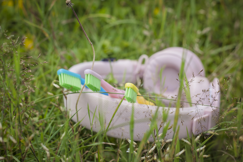 Hörlurar och färgglada tandborstar liggandes i gräs.